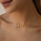 Close-up of a woman wearing the Nella Name Necklace, featuring the name Audrey in elegant cursive letters.