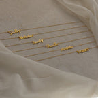 Six Grace Name Necklaces displayed on a beige fabric background, each featuring names in elegant cursive script. Perfect as custom nameplate jewelry for a unique, personal touch.