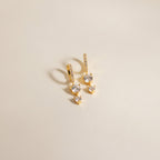 Caroline Pave Drop Huggies: Gold hoops featuring small diamonds and two larger stones on each, shown against a plain light background.