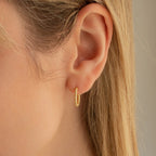 Close-up of a woman's ear wearing Aster Pave Twisted Hoops, with her blonde hair partially covering her ear.