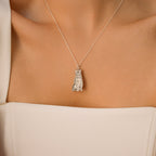 A Custom Pet Portrait Necklace featuring a silver cat pendant amulet is worn on a woman's neck, paired with a white off-shoulder top.