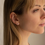 A blonde woman looks off to the side, wearing Booker Large Diamond Studs that add a simple, elegant touch to her everyday style.