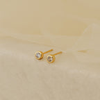 Jane Diamond Studs, featuring small round brilliant diamonds, are elegantly displayed on a soft beige fabric background.