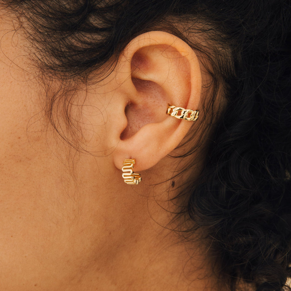 A close-up of a woman’s ear adorned with Maze Half Hoops, creating a unique earring stack.