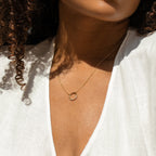 Woman with curly hair wears a white v-neck top and the Kayla Pave Circle Necklace, featuring a minimalistic pave circle design.