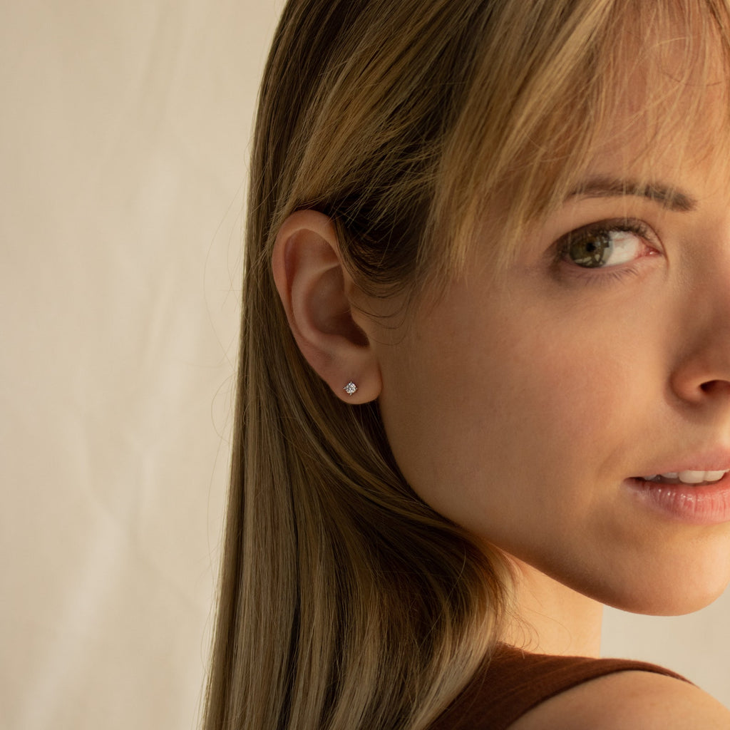 Close-up of a woman with blonde hair wearing Booker Classic Diamond Studs, looking toward the camera.