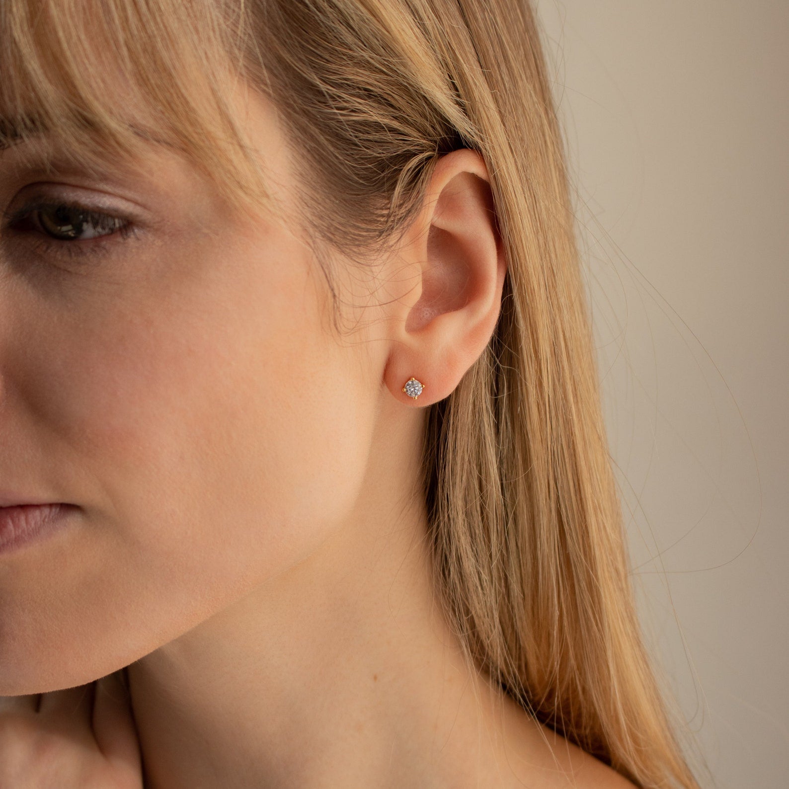 Close-up of a woman wearing Booker Large Diamond Studs in her left ear, with blonde hair partially covering her face—ideal for anyone seeking chic, everyday sparkle.