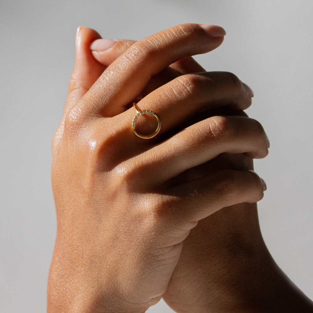 Two hands clasped against a neutral background, with the Pave Open Circle Ring worn as a delicate accent on the index finger.