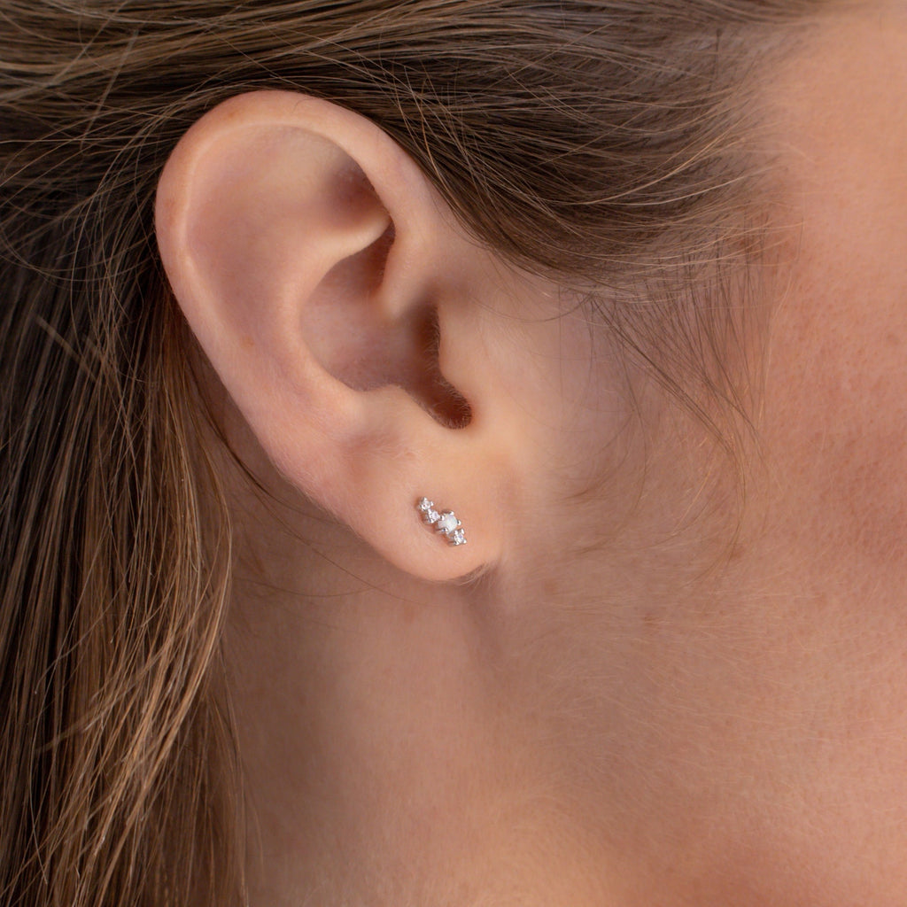 Close-up of a woman's ear wearing Nile Opal and Diamond Studs—a delicate, three-stone design inspired by constellations.