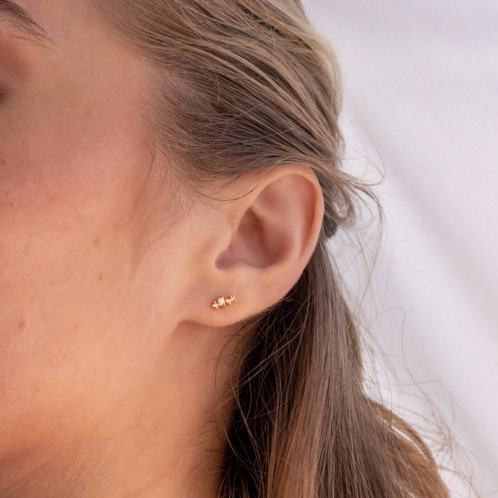 Close-up of a woman’s ear with Nile Opal and Diamond Studs—constellation-inspired earrings—her hair tucked behind her ear.