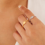 A hand showcases two Eden Sun Rings—one in gold, one in silver—styled boho-chic against a neutral background.