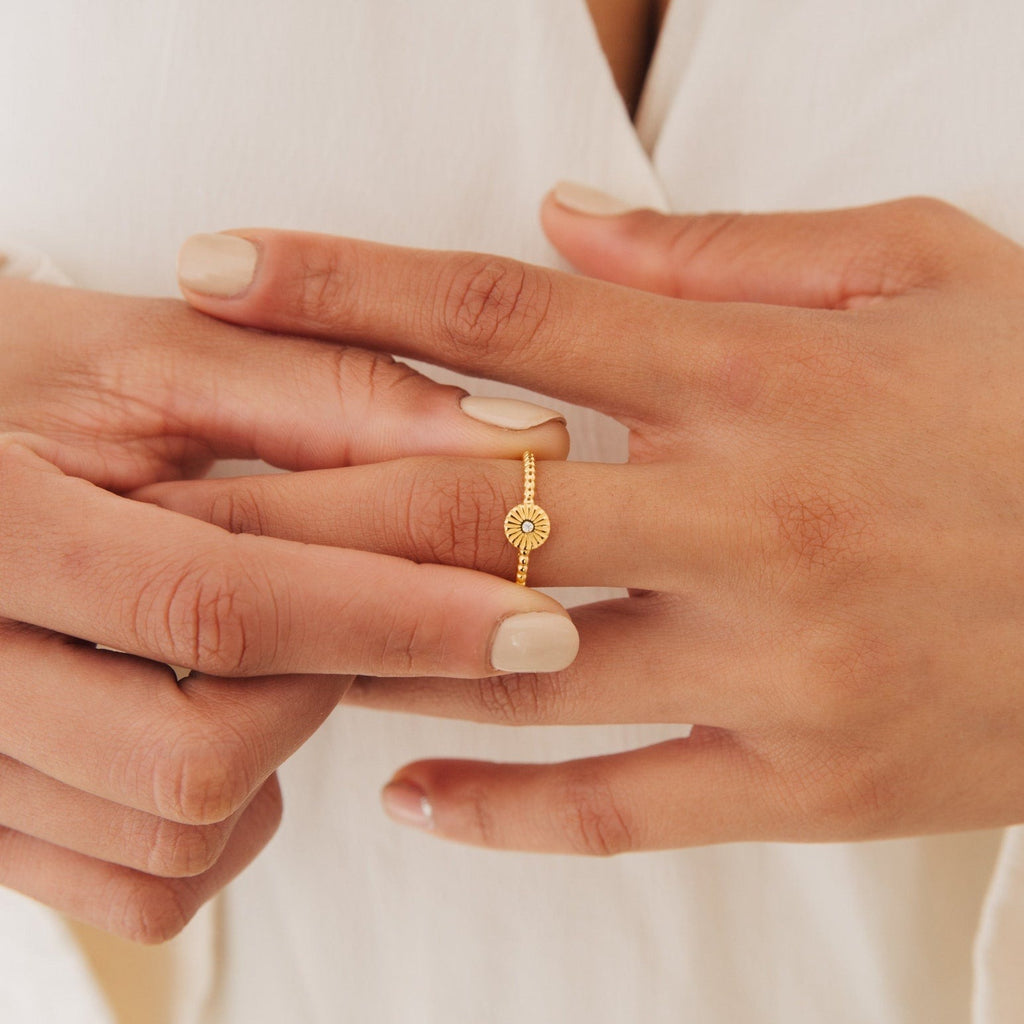 A person wears the Eden Sun Ring on their finger, paired with a cream-colored top for a subtle boho-chic style.