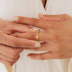 A person wears the Eden Sun Ring on their finger, paired with a cream-colored top for a subtle boho-chic style.