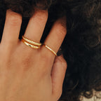 A hand with curly hair wears the Juliet Diamond Ring and two gold rings on the middle and ring fingers.