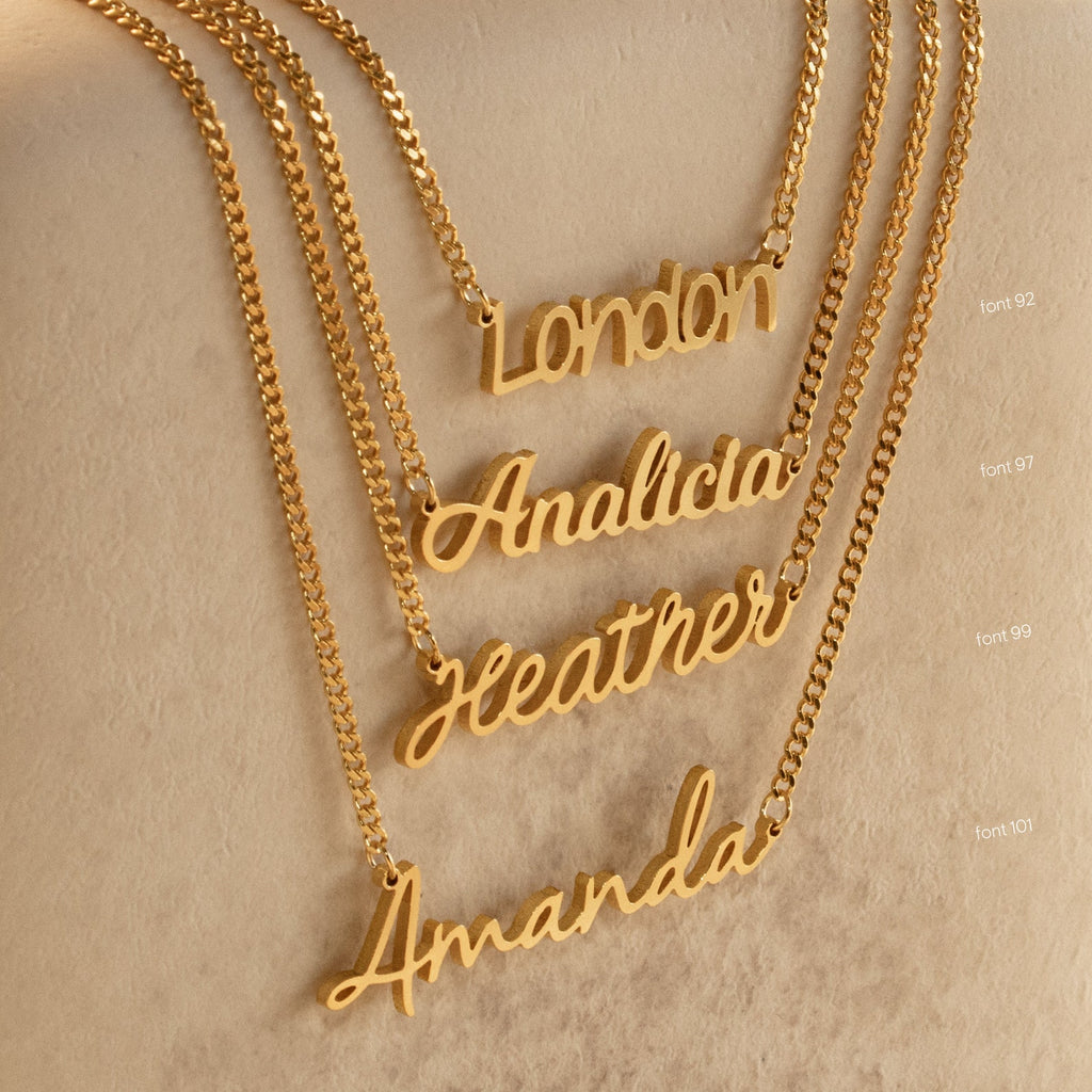 Four gold Mellow Name Necklaces in Curb Chain with name pendants—London, Analicia, Heather, and Amanda—are displayed on a beige surface. This personalized jewelry showcases timeless elegance in a classic font style.