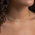 Detailed close-up of a gold choker necklace with five evenly spaced round turquoise blue stones, worn snugly along the base of the neck.
