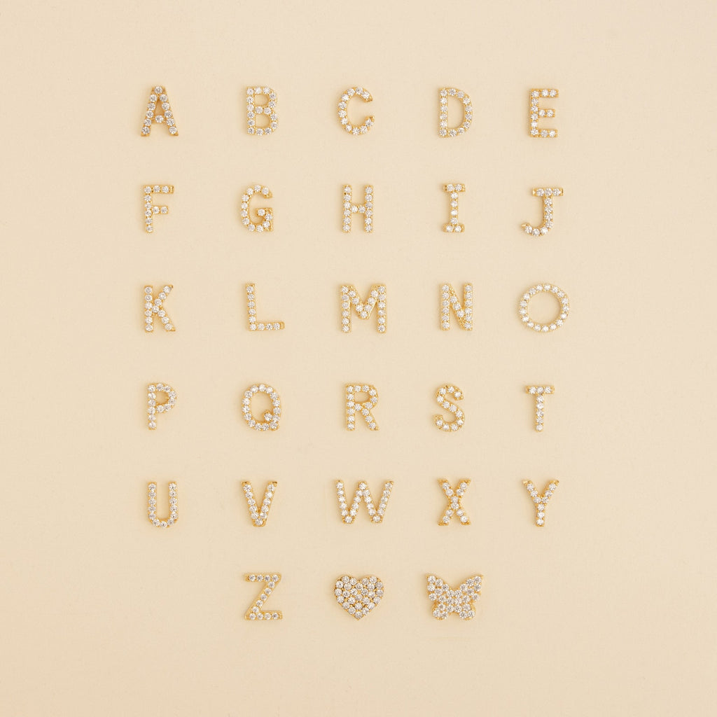 Gold and pearl letters A-Z arranged in rows, with a heart and butterfly at the bottom right—perfect inspiration for the Dangling Pave Initial Necklace, an elegant and thoughtful gift for women.