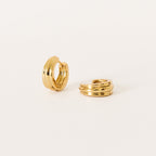 The Canal Chunky Hoops are small gold triple-band huggie earrings with a modern design, ideal for everyday wear. Shown on a plain white background.