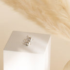 Julia Pearl Studs are displayed on a white block, complemented by soft beige pampas grass in the background.