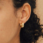 Close-up of a person’s ear with curly hair, wearing Canal Chunky Hoops—layered design earrings that are perfect for a bold, modern everyday look.