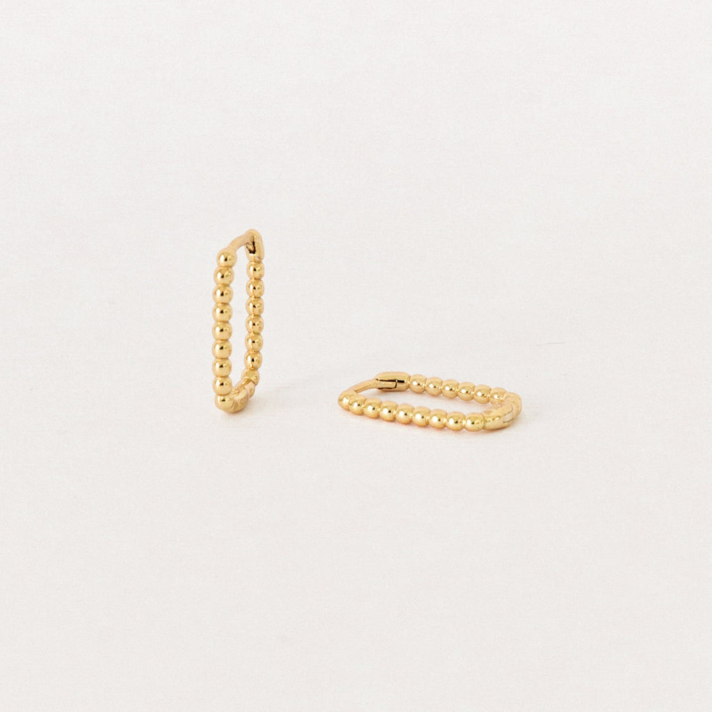 The Indiana Beaded Hoops, a pair of chic gold earrings, are displayed on a plain, light background.
