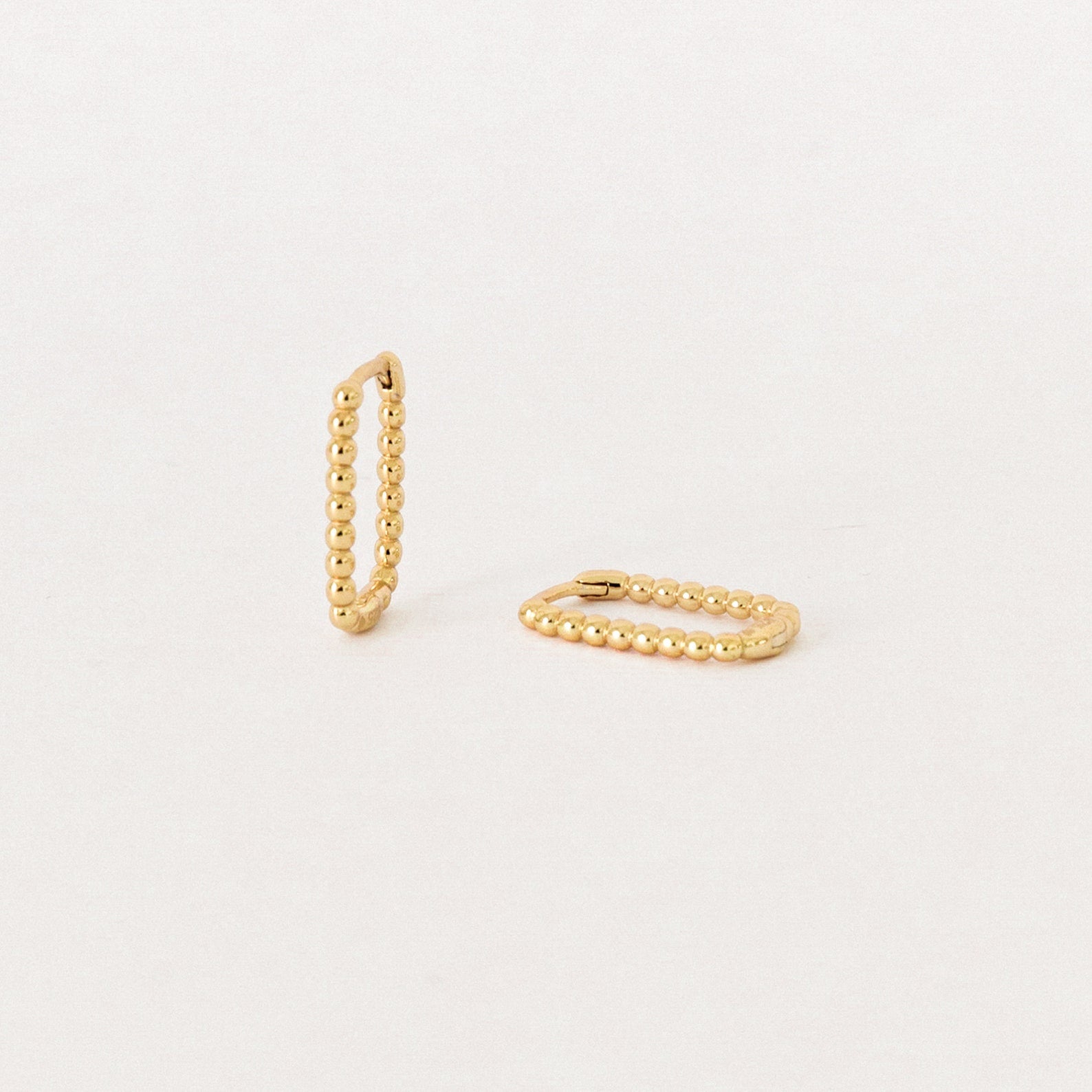The Indiana Beaded Hoops, a pair of chic gold earrings, are displayed on a plain, light background.