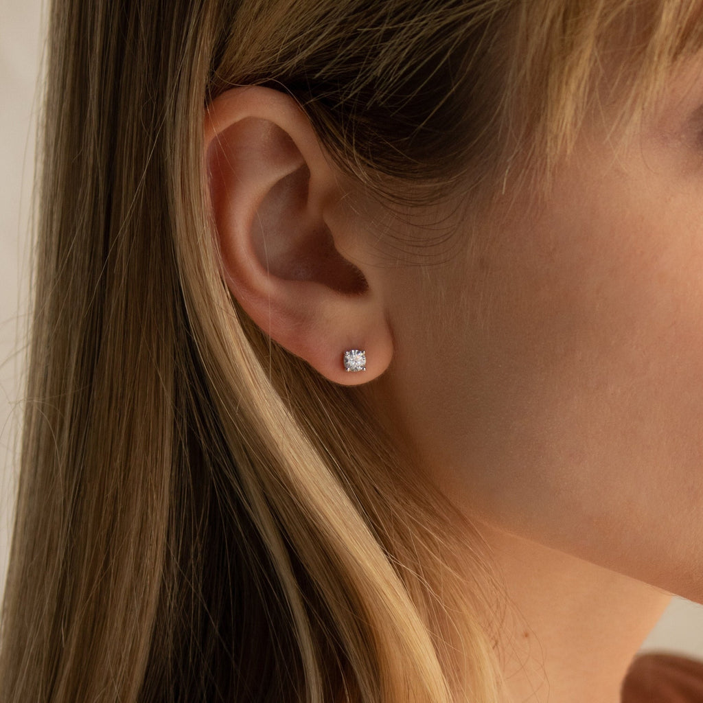 Close-up of a woman's ear wearing the Booker Large Diamond Studs—round, silver minimal earrings with a clear gemstone, perfect for everyday wear.