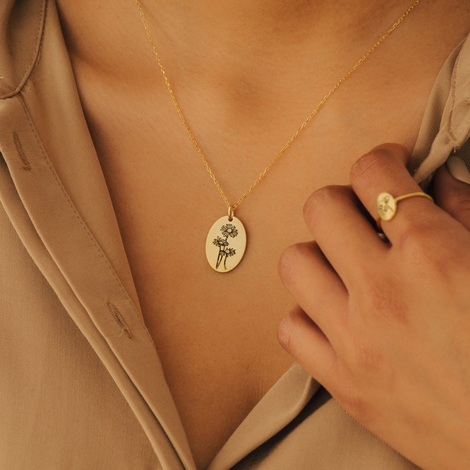 The Oval Flower Necklace features a unique flower pendant worn on the neck, perfectly complemented by a matching gold ring.