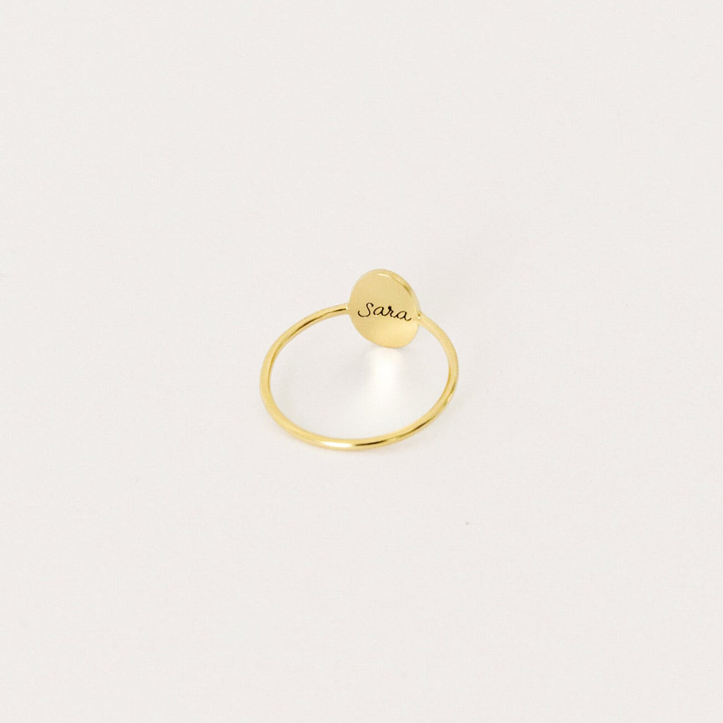 The Flower Oval Ring features a small, oval engraved plate reading "Sara," captured against a plain white background—a perfect personalized jewelry piece for a meaningful touch.