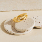 Flat lay of Chelsea Duo Ring in gold with rope and smooth band detail placed on speckled stone props.