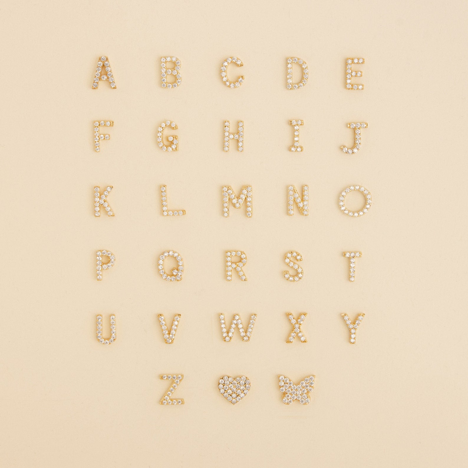 The Pave Initial Heart Necklace features gold, diamond-studded alphabet letters and a heart charm—ideal for creating your own custom initial or handmade diamond necklace.