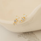 Maeve Opal Studs: Gold statement earrings accented with two white stones and two clear crystals per earring, displayed on a cream ceramic dish.