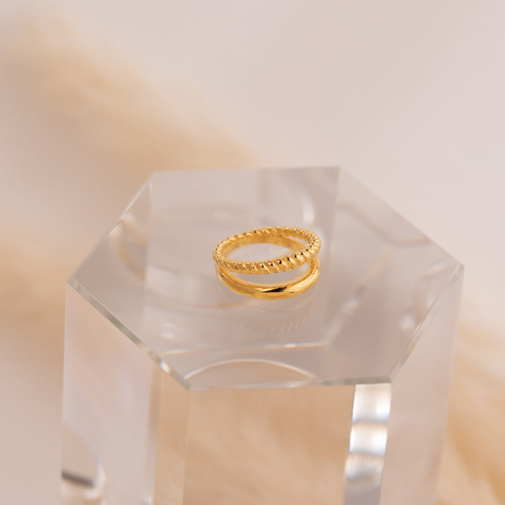 Chelsea Duo Ring in gold displayed on a clear acrylic block with soft beige backdrop.