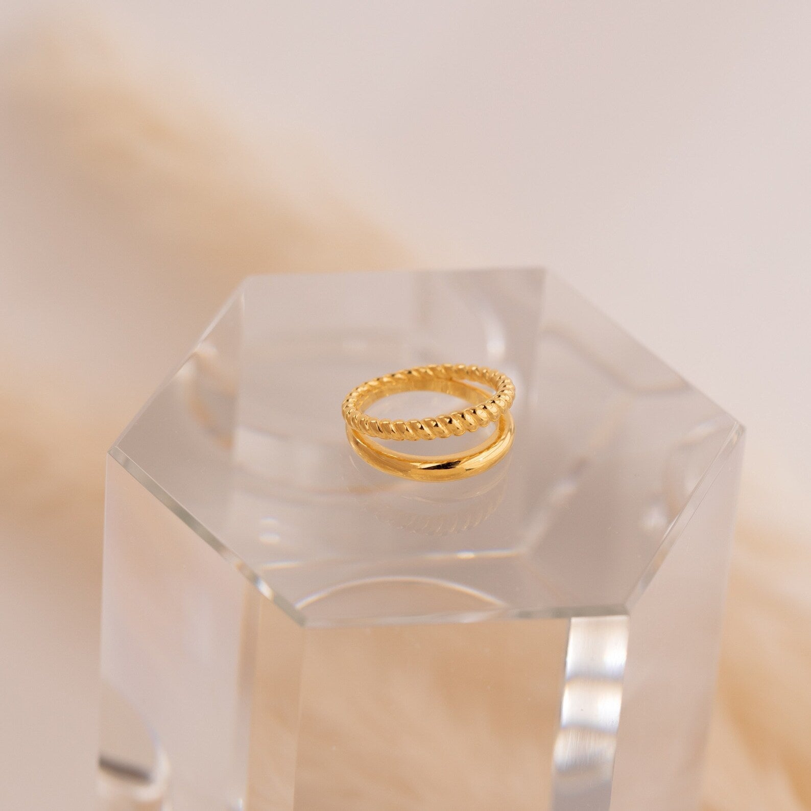 Chelsea Duo Ring in gold displayed on a clear acrylic block with soft beige backdrop.