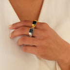 Hand wearing the Black Signet Ring and a silver band against a white v-neck background. This unisex Black Signet Ring is a striking accessory, ideal for making a bold statement with any outfit.