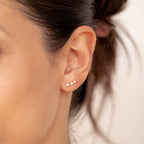 Close-up of a woman's ear wearing two small gemstone earrings—one gold stud and one clear stone—ideal for mixing with Maeve Opal Studs or pairing with other statement pieces.