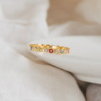 The Rainbow Evil Eye Ring features round, colorful enamel accents and sparkling clear stones, making it an eye-catching lucky charm displayed stylishly on white fabric.