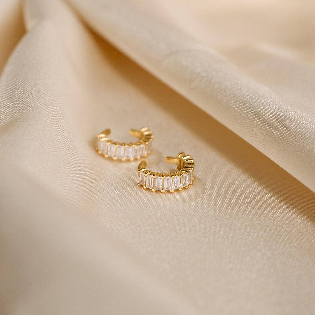 Baguette Ear Cuffs, shown with gold hoop earrings featuring rectangular crystals on champagne satin, add a modern and elegant touch to your look.