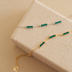 The Malachite Bar Bracelet, available in silver and gold with green rectangular stones, features a dainty chain design. Perfect for stacking or wearing solo, this handmade piece adds a subtle boho touch to any look.