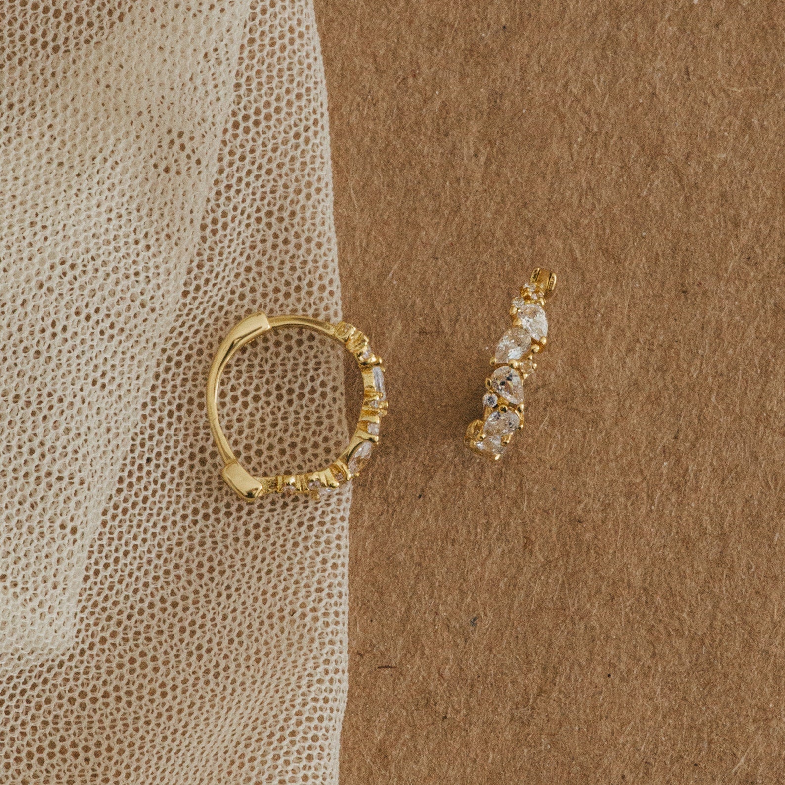 Pair of Sprinkle Diamond Huggies resting on fabric