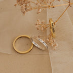 The Stacking Flower Band, alongside a slim gold band and an engraved silver ring, is displayed on tulle beside dried flowers, highlighting the botanical elegance of this jewelry piece.