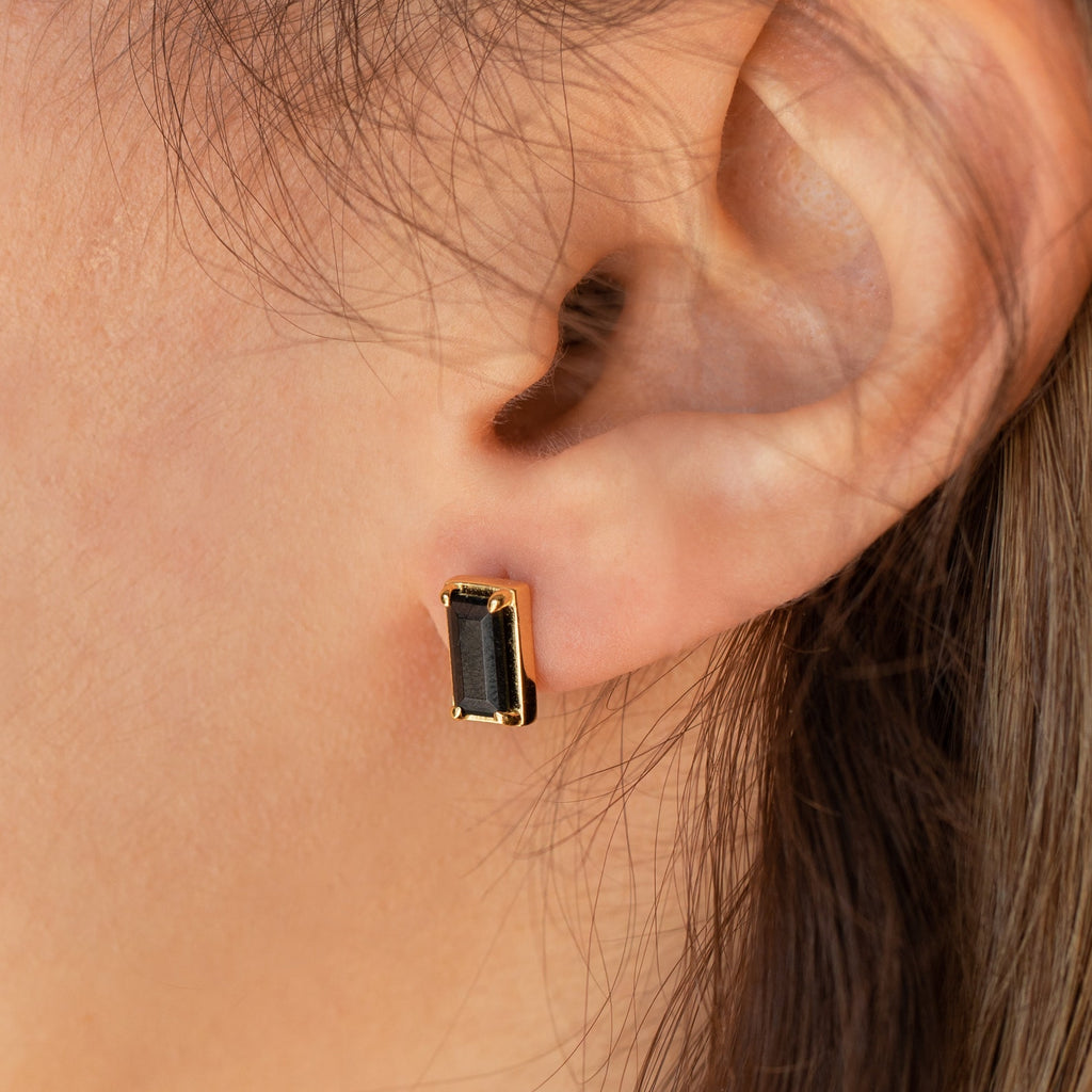 Close-up of an ear wearing Rectangle Black Onyx Studs, showcasing the chic black and gold earrings.