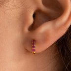 Close-up of an ear wearing the Elise Gemstone Huggies Set—a small gold hoop adorned with five pink gemstones, perfect for those who love unique artisan-made earrings.