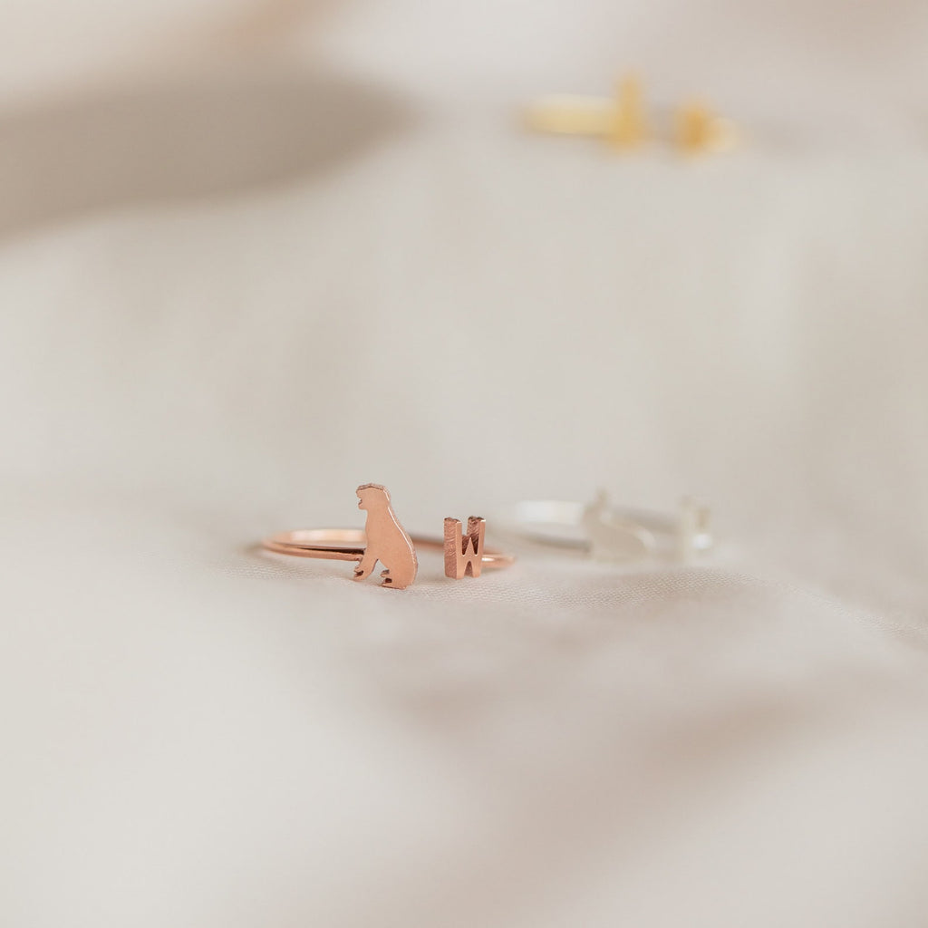Close-up of the Duo Pet Initial Ring, a rose gold band shaped like a sitting cat, displayed on soft, light-colored fabric—an elegant piece of personalized pet jewelry.