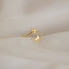 The Duo Pet Initial Wrap Ring showcases a cat and cursive "G" design, displayed on soft beige fabric—an ideal personalized jewelry piece for cat lovers.