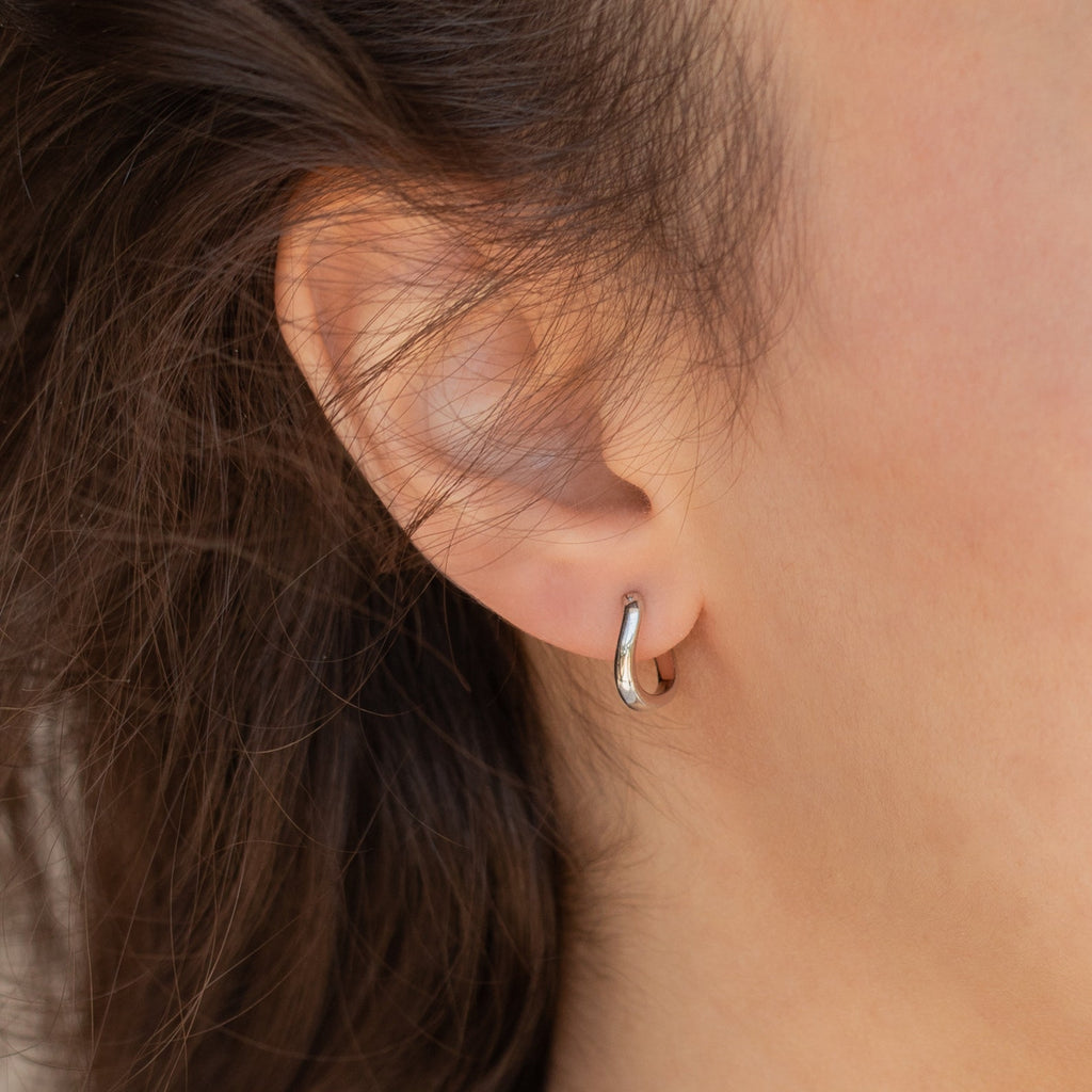 Close-up of a person's ear wearing the McKenna Abstract Hoops—small, simple silver earrings that make an elegant everyday choice.