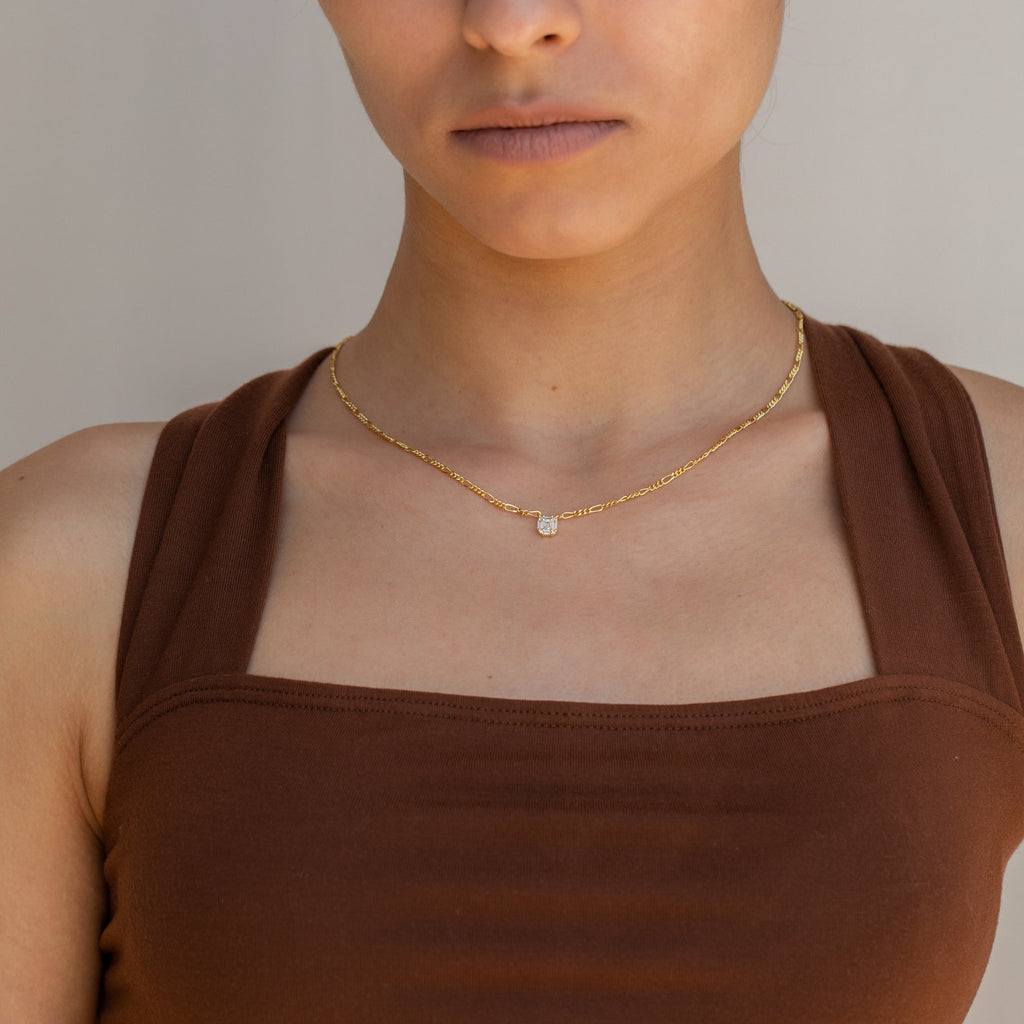 Woman wearing a brown sleeveless top and the Square Diamond Figaro Necklace with a small pendant, shown from shoulders up.