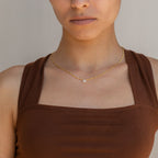 Woman wearing a brown sleeveless top and the Square Diamond Figaro Necklace with a small pendant, shown from shoulders up.