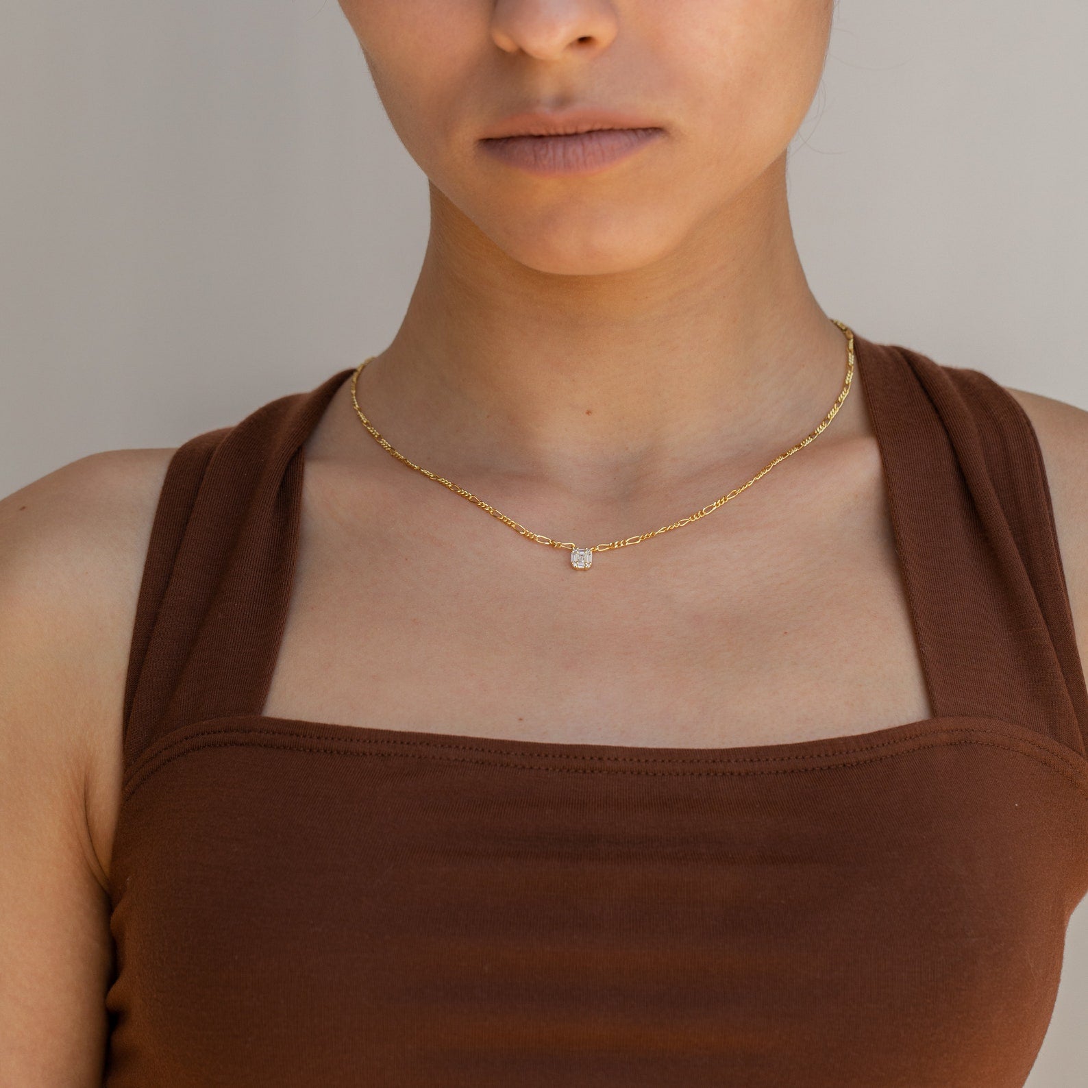 Woman wearing a brown sleeveless top and the Square Diamond Figaro Necklace with a small pendant, shown from shoulders up.