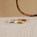 The Skinny Flower Ring is shown in silver, gold, and rose gold on a textured surface. This botanical jewelry adds delicate elegance to any look, making it a perfect unique accent.